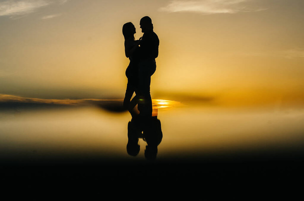 silueta milujícího páru objímajícího se při západu slunce - Fotografie, Obrázek