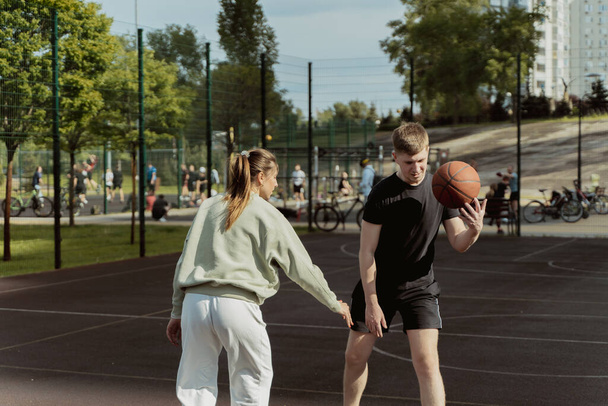 девочка и мальчик играют в баскетбол на баскетбольной площадке - Фото, изображение