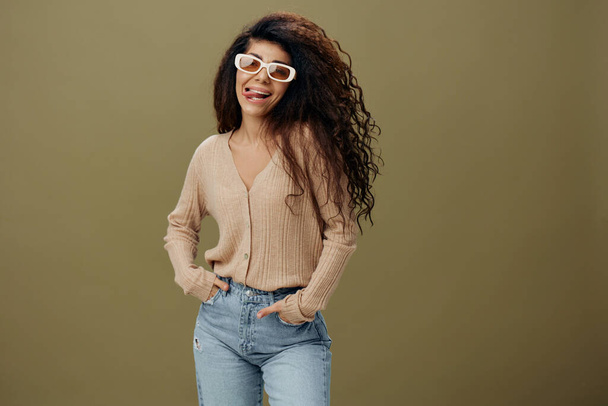 FASHION CONCEPT. Enjoyed pretty tanned curly Latin female in casual things sunglasses hold hand on jeans posing isolated over pastel olive green background. Copy space Mockup Banner. Fashion offer - Photo, Image