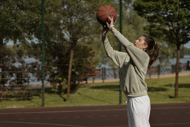 girl throws the ball into the ring on the basketball court - 写真・画像