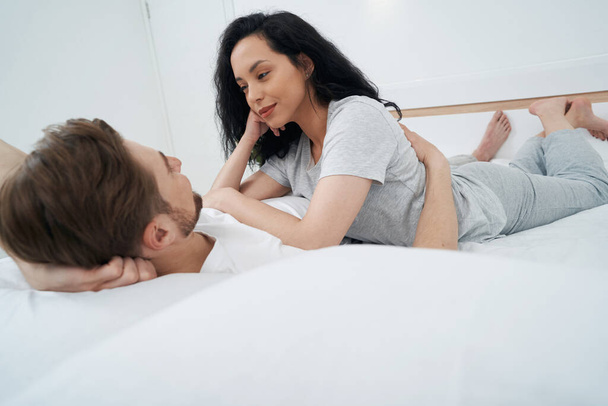 Romantic female lying on chest of her life partner and staring at him - Photo, Image