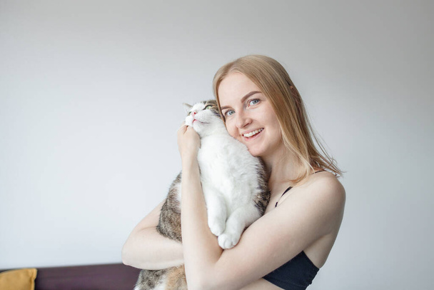 Kadın, evde kediye sarılıyor. Evde kal. Kendine dikkat et. Aşk, bakım, evlat edinme - Fotoğraf, Görsel