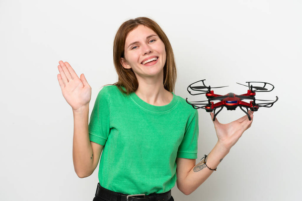 Young English woman holding a drone isolated on white background saluting with hand with happy expression - Φωτογραφία, εικόνα