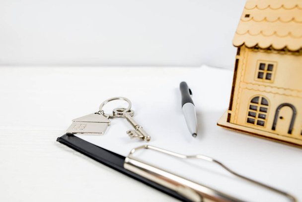 dřevěný dům s perem klíče a schránka na bílé.key s klíčenky ve tvaru domu.Hypotéka koncept. Nákup, relokace, půjčka, pronájem nemovitostí. - Fotografie, Obrázek