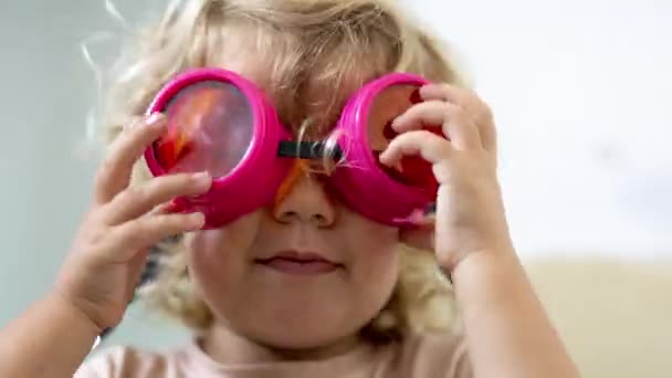 Egy gyors mozgású sorozat egy kislányról túlméretezett változó napszemüvegben. - Felvétel, videó