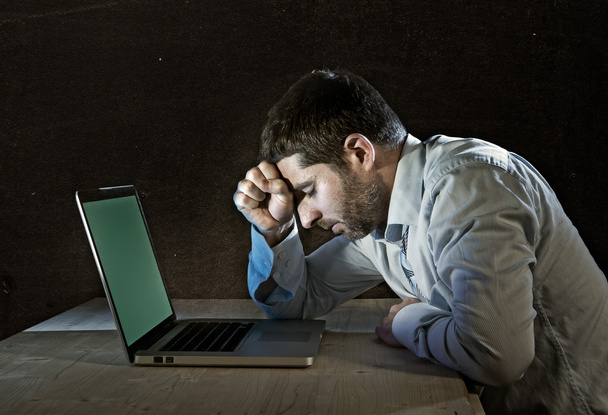 Młody podkreślił biznesmen działa na biurko z komputerem laptop w frustrację i depresji - Zdjęcie, obraz