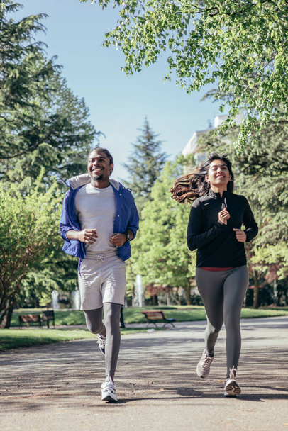 multi-ethnic runner couple joggin in park - 写真・画像
