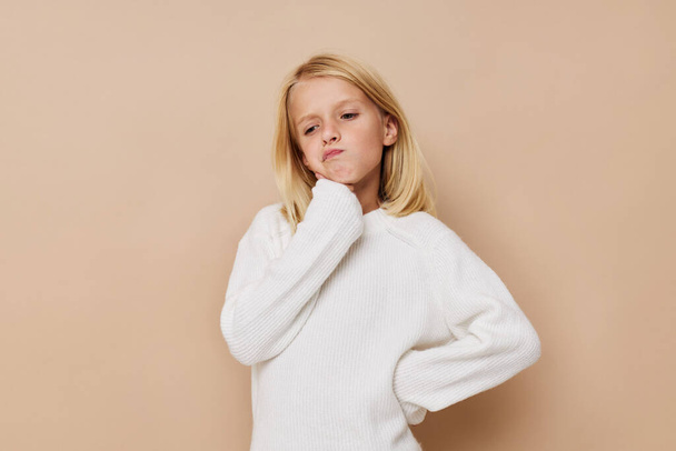 happy cute girl in a sweater, grimaces on a beige background. High quality photo - Фото, изображение