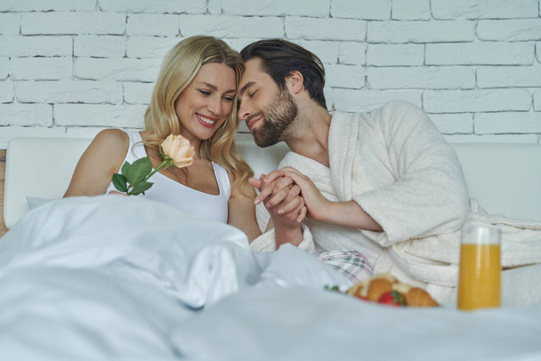 Cute loving couple bonding while having breakfast in bed - Fotó, kép