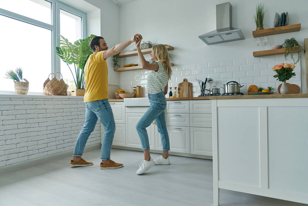 Full length of young loving couple dancing at the domestic kitchen - Foto, afbeelding