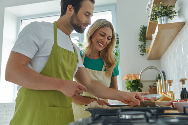 Young loving couple making homemade pizza while standing at the kitchen together - Foto, imagen