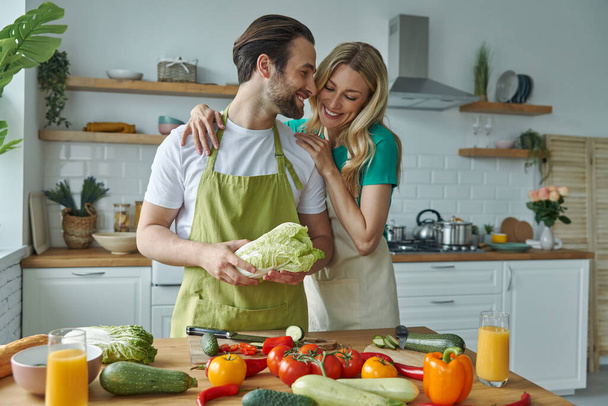 Veselý mladý pár vaří společně v domácí kuchyni - Fotografie, Obrázek