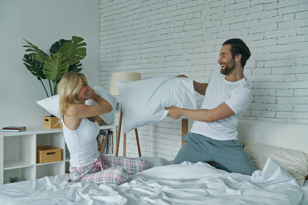 Carefree young couple enjoying pillow fight in the bed at home - Fotografie, Obrázek