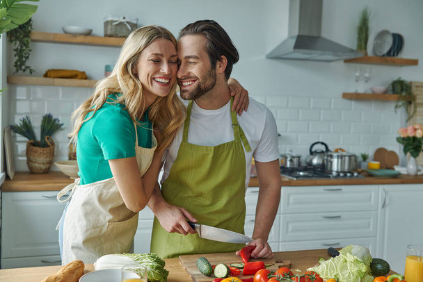 Cheerful young couple cooking together and bonding at the domestic kitchen - Foto, imagen