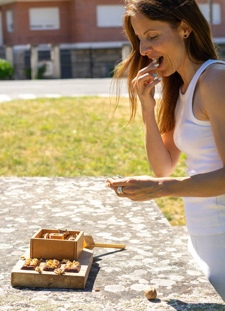 žena nosí v ústech ořech, který se rozbil dřevěným kladivem  - Fotografie, Obrázek