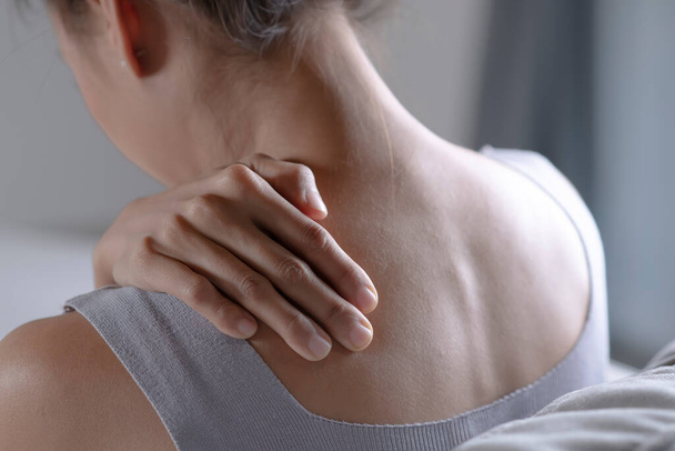 Asian woman has shoulder pain. Female holding painful shoulder with another hand. People with body-muscles problem, Healthcare And Medicine. - 写真・画像