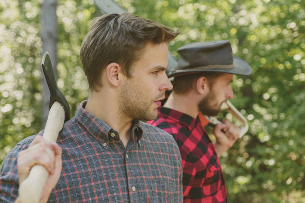 Man with axe in forest. Lumberjack woodcutter in a plaid shirt. Lumberjack brutal bearded man. - Foto, Imagem