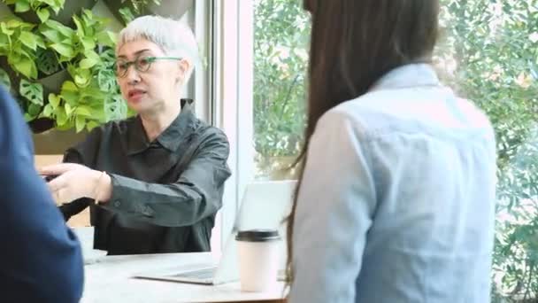 Senior nő beszél beleegyezését projekt és aláírja tabletta üzletemberek a kávézóban, idős beszélgetés és foglalkozik partnerség üzleti a kávézóban, tanácsadó és ügynök. - Felvétel, videó