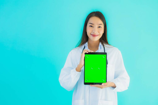 Portrait beautiful young asian doctor woman with stethoscope and smart tablet for use in hospital and clinic on blue isolated background - Photo, Image