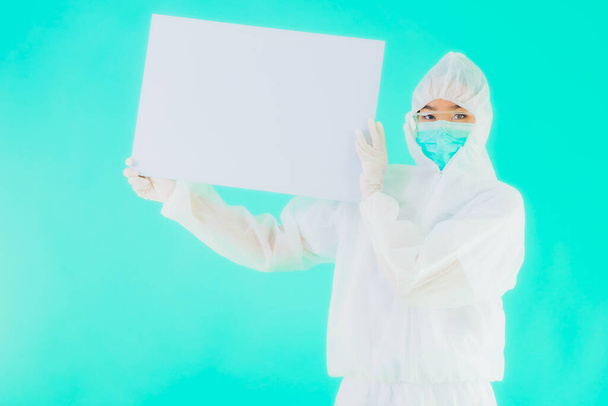 Muotokuva kaunis nuori aasialainen lääkäri nainen käyttää ppe tai henkilökohtaisia suojavarusteita suojaamaan koronavirukselta tai covid19 tyhjällä kortin valkoisella aluksella sinisellä eristetyllä taustalla
 - Valokuva, kuva