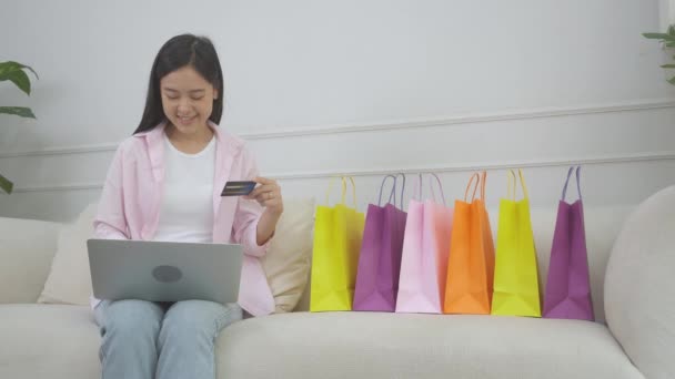 Молодая азиатская женщина, сидящая на диване с помощью ноутбука компьютер покупки онлайн с кредитной картой покупки в Интернет, счастье девушка платить транзакцией финансовых, покупка и оплата, бизнес-концепция. - Кадры, видео