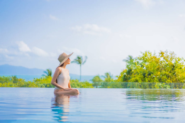Portret mooie jonge aziatische vrouw genieten rond openlucht zwembad met uitzicht op zee in reizen vakantie - Foto, afbeelding