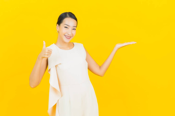 Portrait beautiful young asian woman smile with action on yellow color background - Фото, изображение
