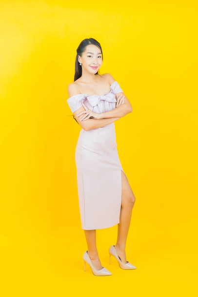 Portrét krásná mladá asijská žena úsměv s akcí na barevném pozadí - Fotografie, Obrázek