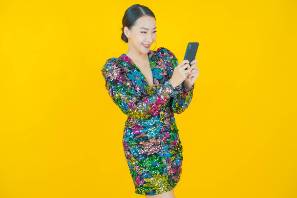 Porträt schöne junge asiatische Frau lächeln mit Smartphone auf farbigem Hintergrund - Foto, Bild