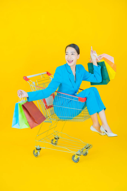 Retrato bonito jovem asiático mulher sorriso com mercearia cesta de supermercado na cor de fundo - Foto, Imagem