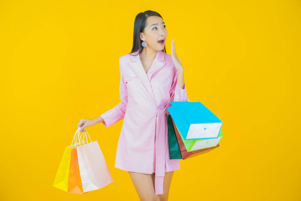 Portrait beautiful young asian woman smile with shopping bag on color background - Foto, Imagem