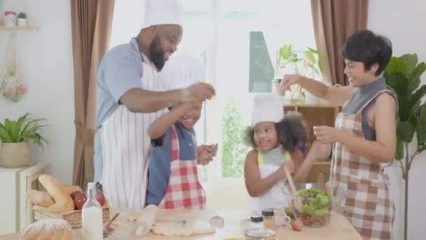 Afro-Amerikan ailesi yemek pişirmek ve dans etmek için önlük takıyor. Mutfakta birlikte eğleniyorlar. Ebeveynler ve küçük çocuklar yemeklerini eğlenceli ve eğlenceli bir şekilde hazırlıyorlar.. - Video, Çekim