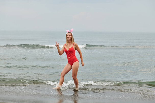in einem roten Badeanzug Mädchen am Meer mit Hasenohren. Hochwertiges Foto - Foto, Bild