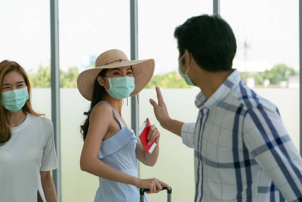 Havaalanında maskeli genç Asyalı gezginler yeni normal bir yaşam tarzıyla karşılanıyorlar. Coronavirus covid-19 konsepti. - Fotoğraf, Görsel