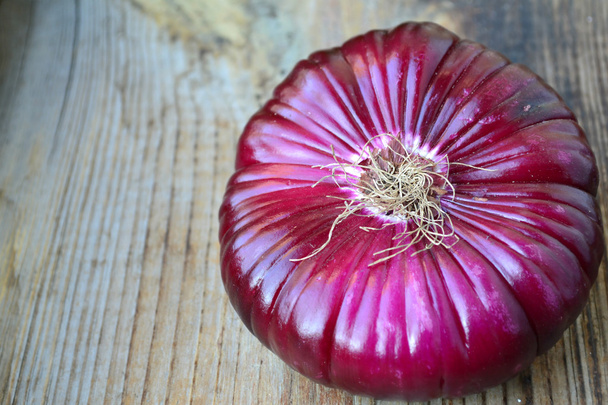 Big red onion on wooden table - Foto, afbeelding