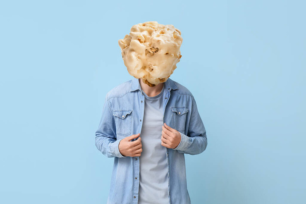 Man with tasty popcorn ball instead of his head on light blue background - Foto, immagini