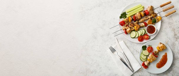 Plates with grilled chicken skewers, vegetables and sauce on light background with space for text - Fotoğraf, Görsel