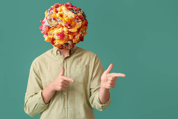 Kafası yeşil arka plandaki bir şeyi işaret etmek yerine lezzetli patlamış mısır toplu bir adam. - Fotoğraf, Görsel