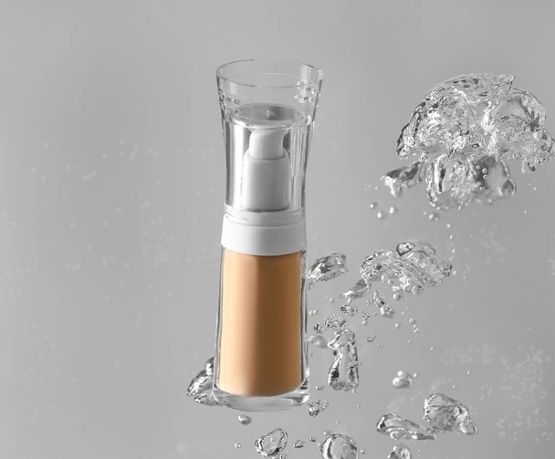 Flasche Make-up Foundation in Wasser auf grauem Hintergrund - Foto, Bild