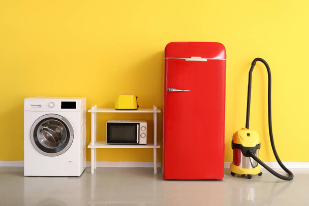 Eletrodomésticos modernos perto da parede amarela no quarto - Foto, Imagem