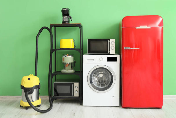 Eletrodomésticos modernos perto de parede verde no quarto - Foto, Imagem
