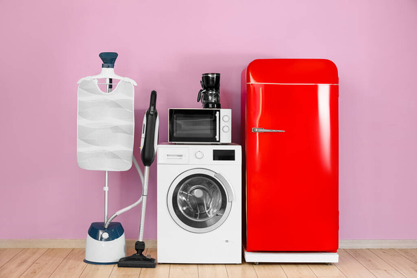 Modern household appliances near pink wall in room - Photo, Image