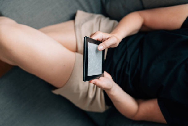 Mature middle age woman dealing e-book at home on the couch. High quality photo - Fotoğraf, Görsel
