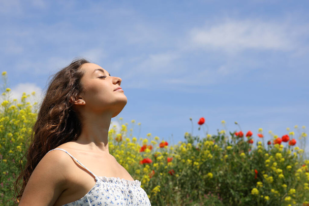 Relaxed woman breathing fresh air in a flowers field - Foto, imagen