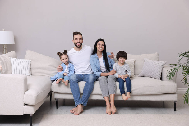 Portrait of happy family on sofa in living room - Foto, afbeelding