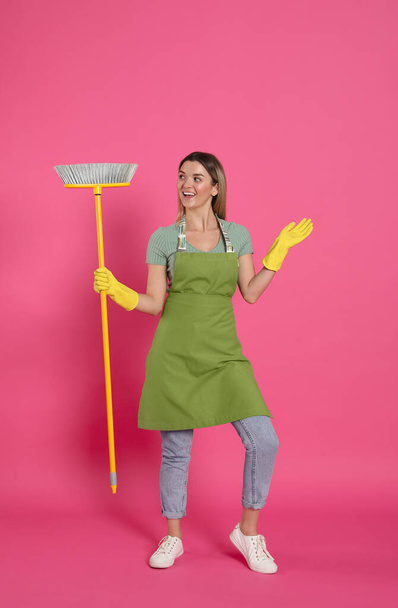 Young woman with yellow broom on pink background - Fotó, kép