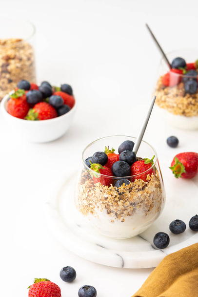 Homemade granola with almonds in a glass with yogurt, fresh strawberries and blueberries, delicious healthy breakfast - Photo, Image