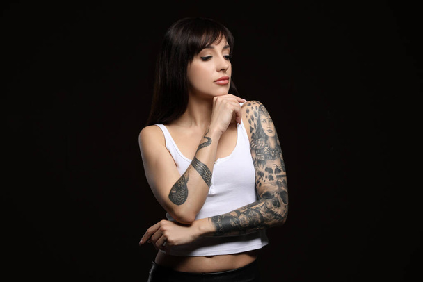 Beautiful woman with tattoos on arms against black background - Fotoğraf, Görsel
