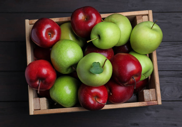Fresh ripe red and green apples in wooden crate on black table, top view - Φωτογραφία, εικόνα