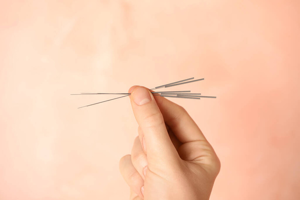Woman holding needles for acupuncture on pink background, closeup - Foto, Bild